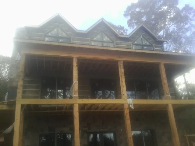 Dormers and porch framing on a large log home under construction — Roof Coating work by our crew in Galena