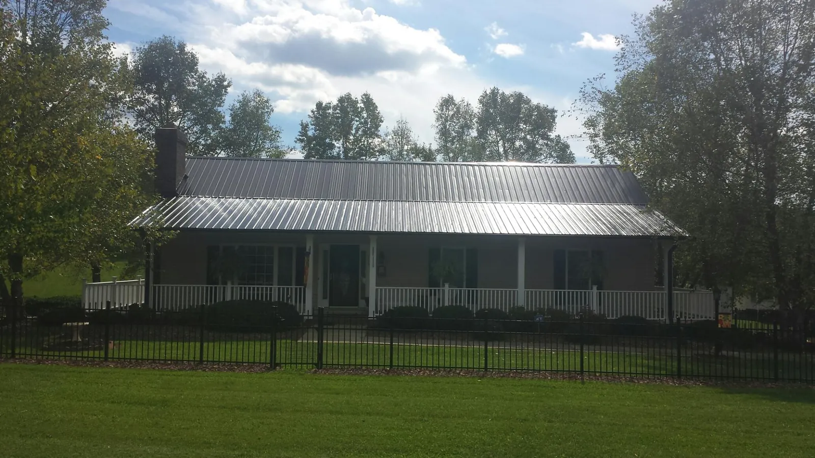 Gray metal roof on a brick ranch with a full width front porch — Gutter Guard Installation work by our crew in Galena