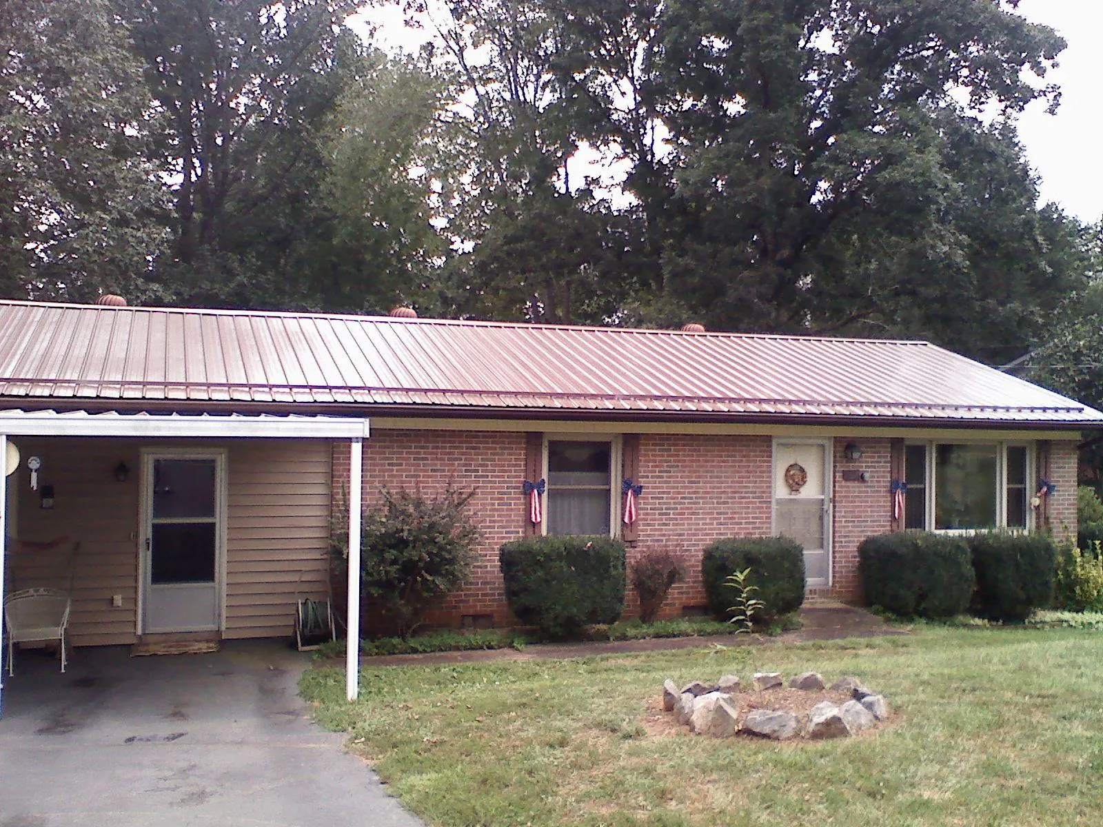 Bronze metal roof and carport on a brick ranch home — Roof Repair work by our crew in Galena